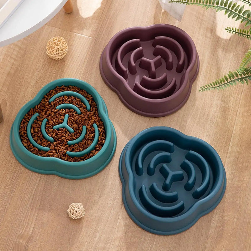 Three silicone pet feeding bowls in teal, purple and navy blue with maze-like designs.